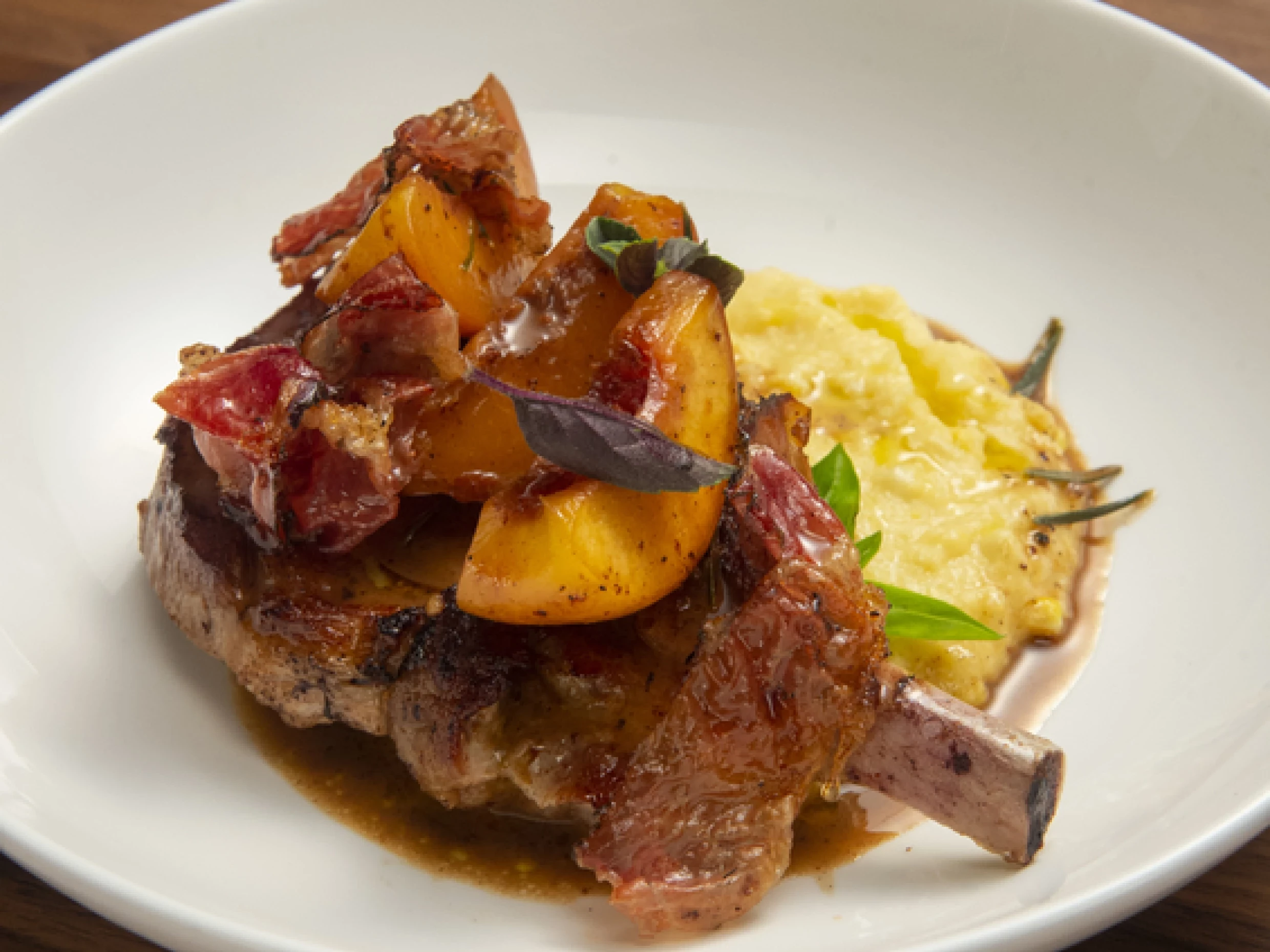 stuffed pork chops on a plate topped with peach polenta