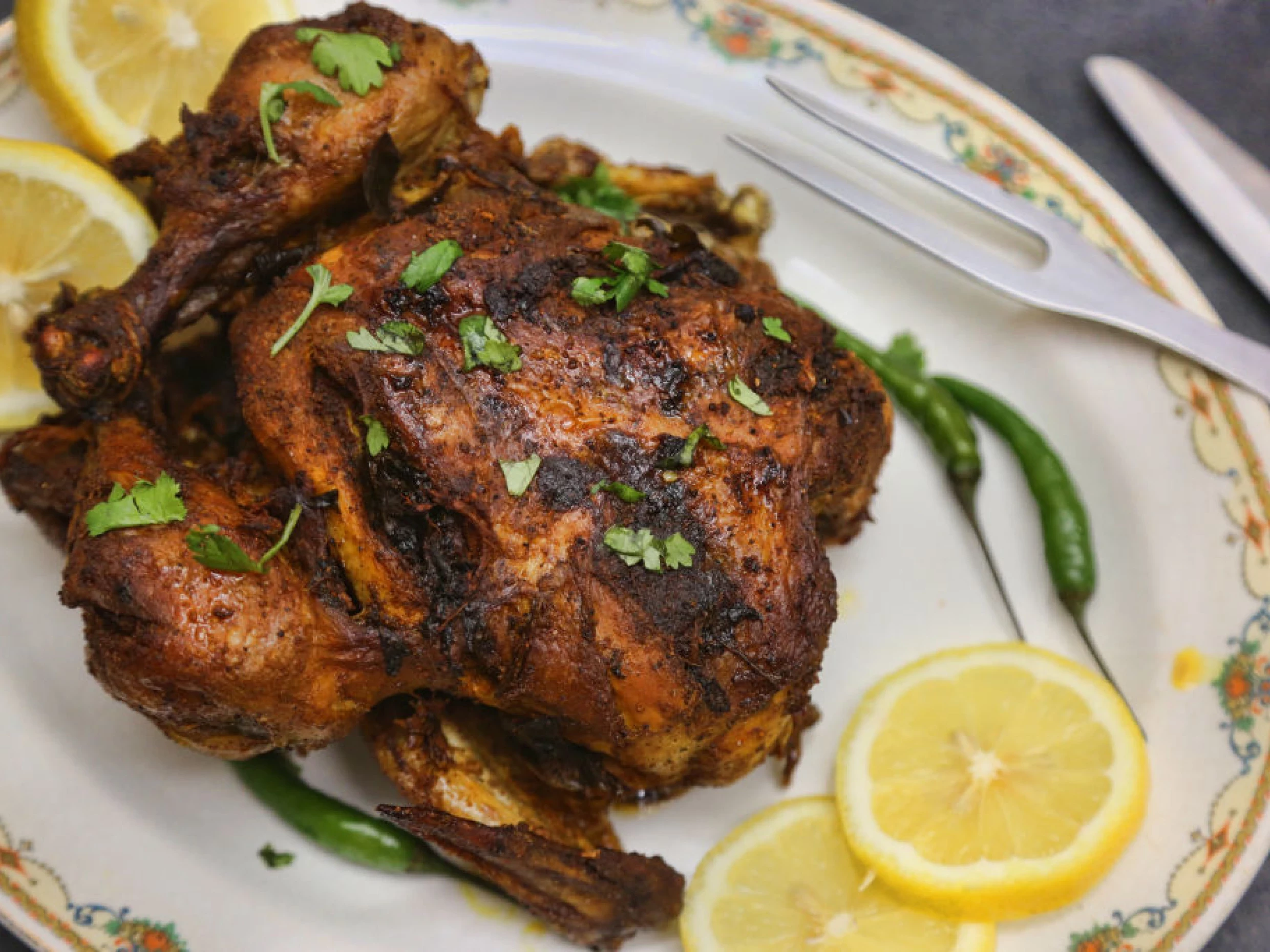 whole garlic roasted chicken served on a platter with lemon slices