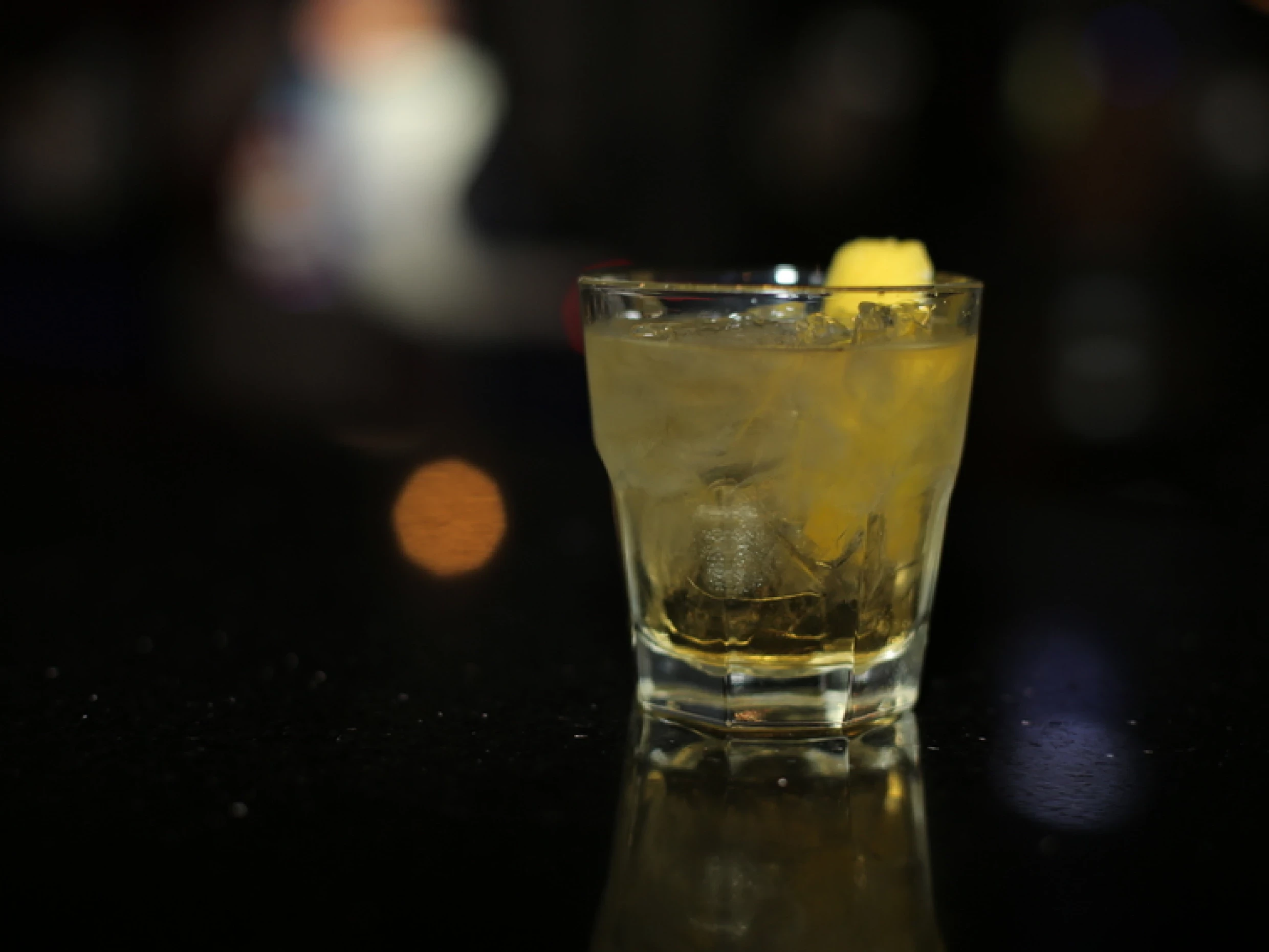 a rusty nail cocktail with a slice of lemon as garnish