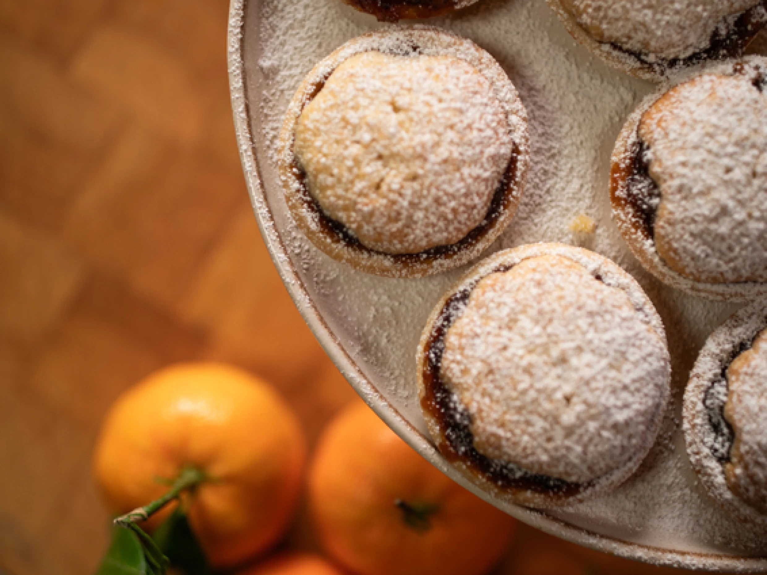 Plate of mince pies top shot top right corner with oranges in the backgroun