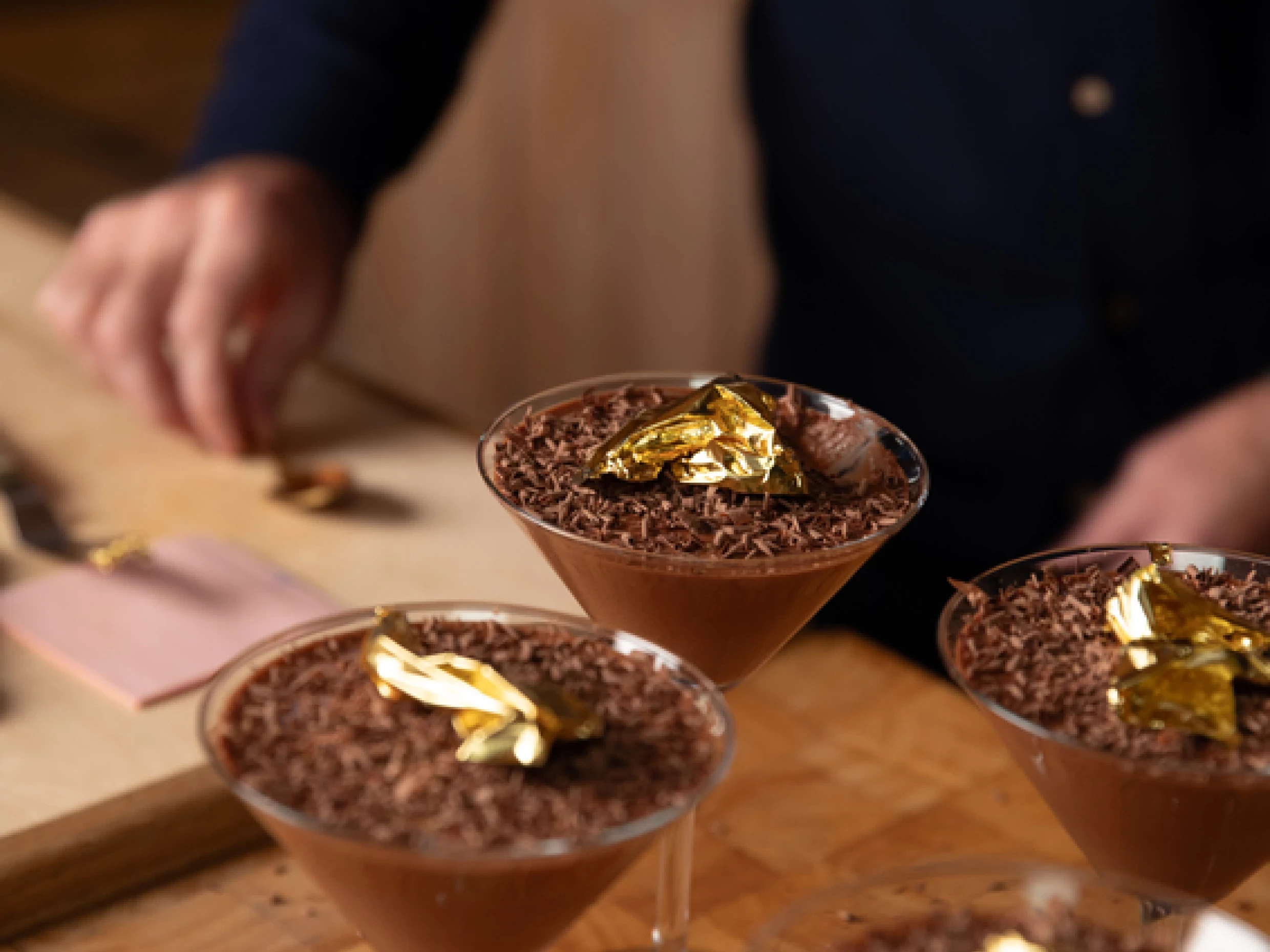4 martini glasses filled with chocolate mousse with a floral garnish on top.