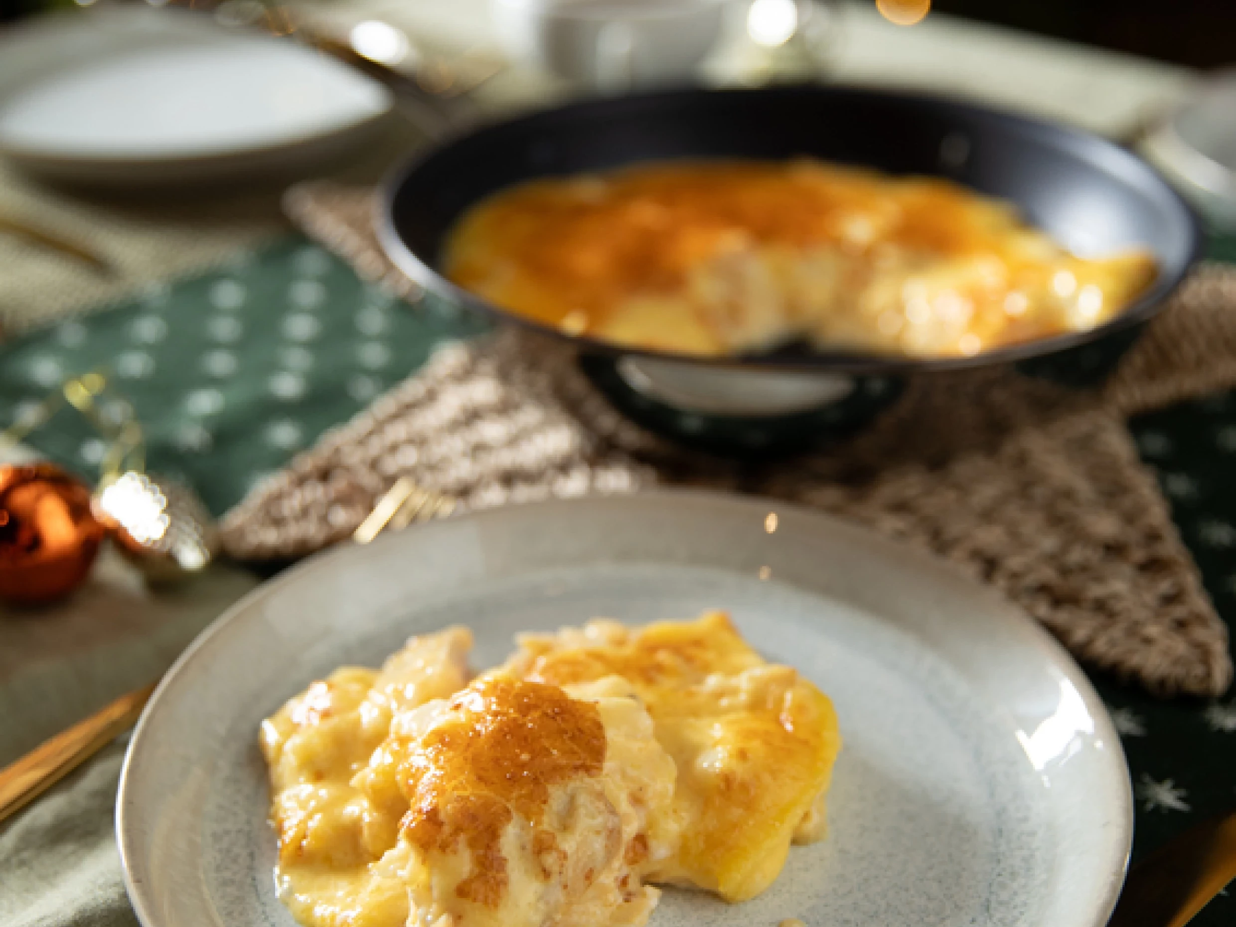 A fluffy omelette served on a plate with the full dish and christmas lights in the background