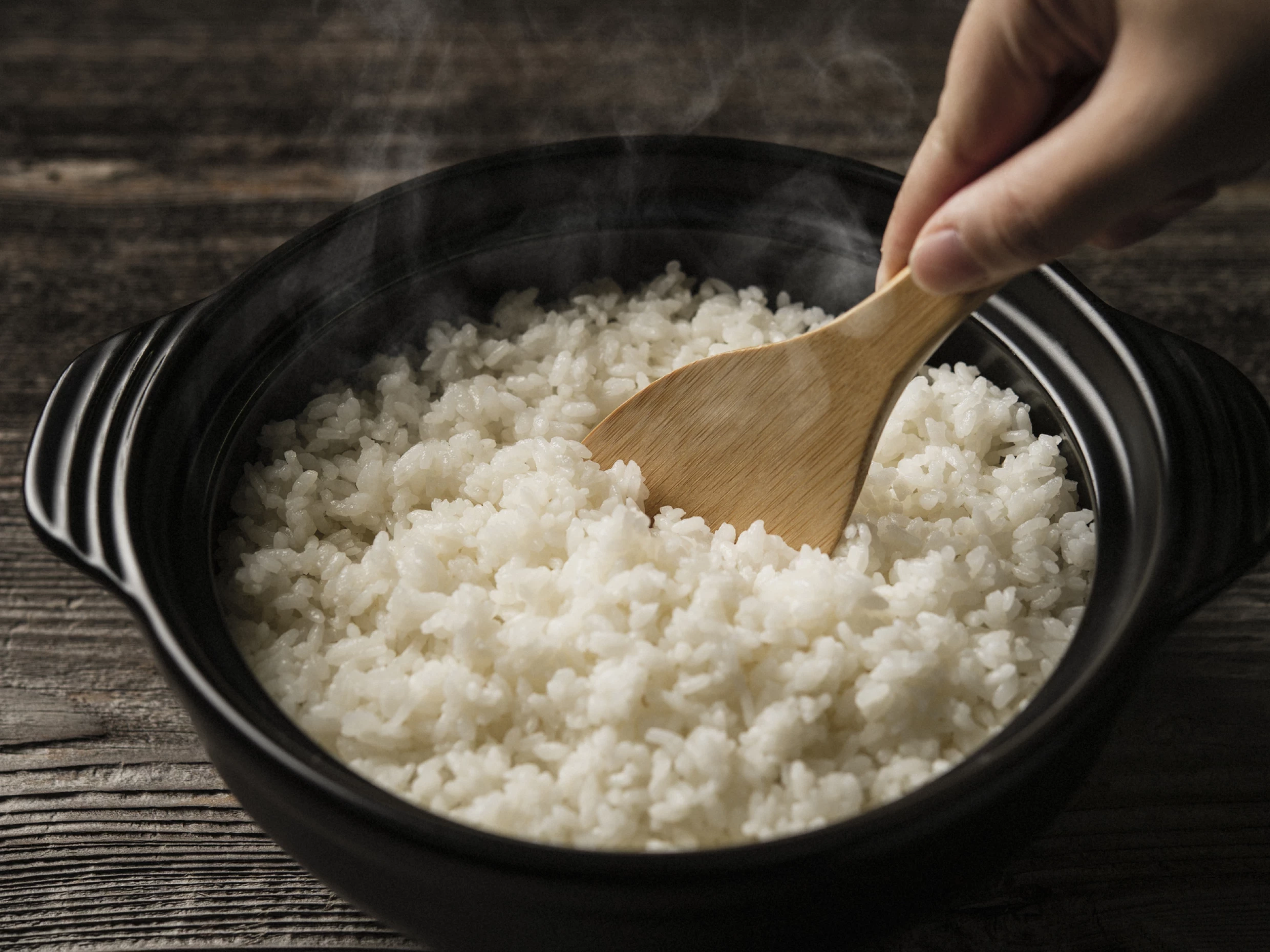 rice being mixed with wooden spoon