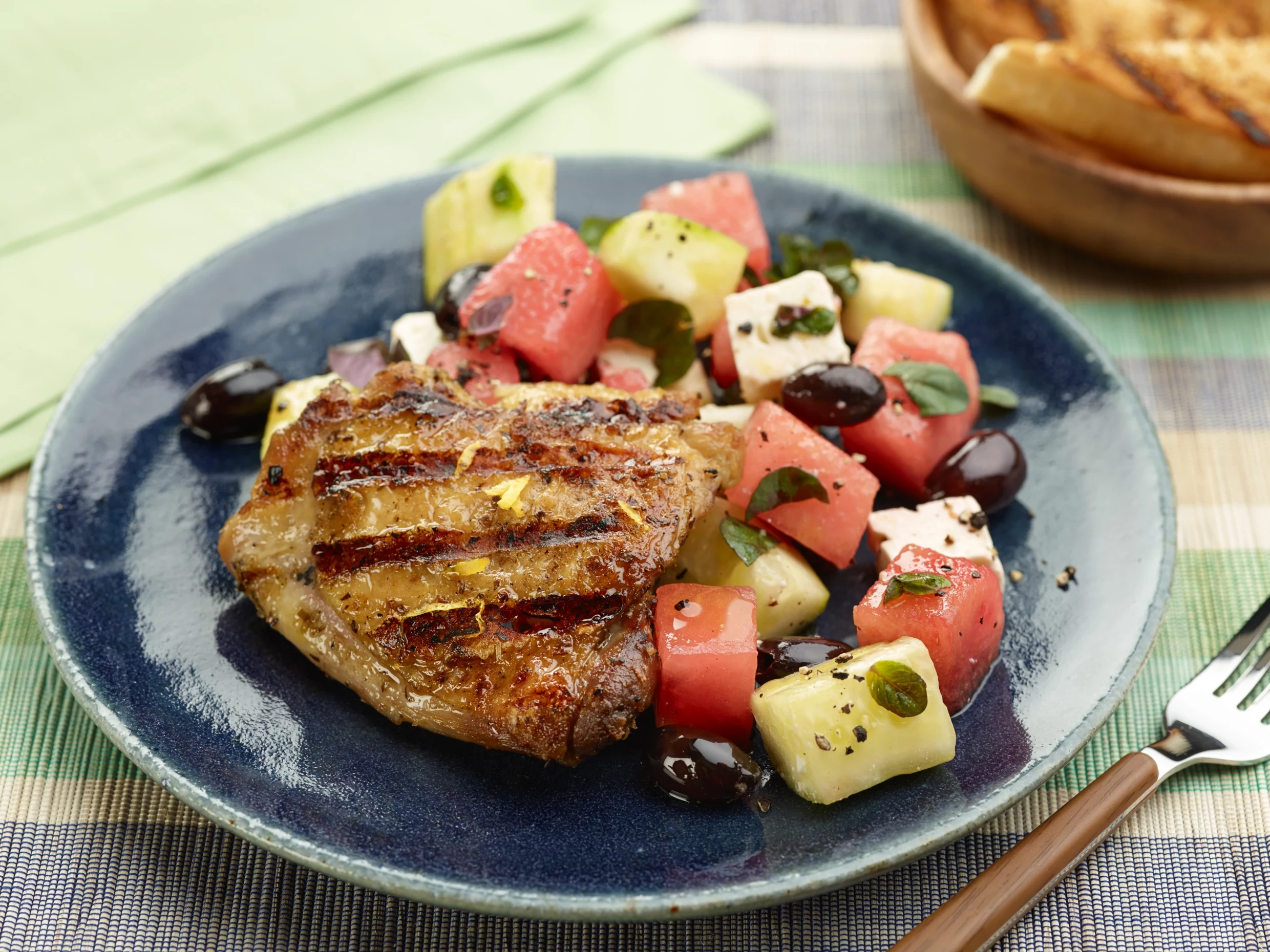 chicken thighs on a plate with a fresh watermelon salad