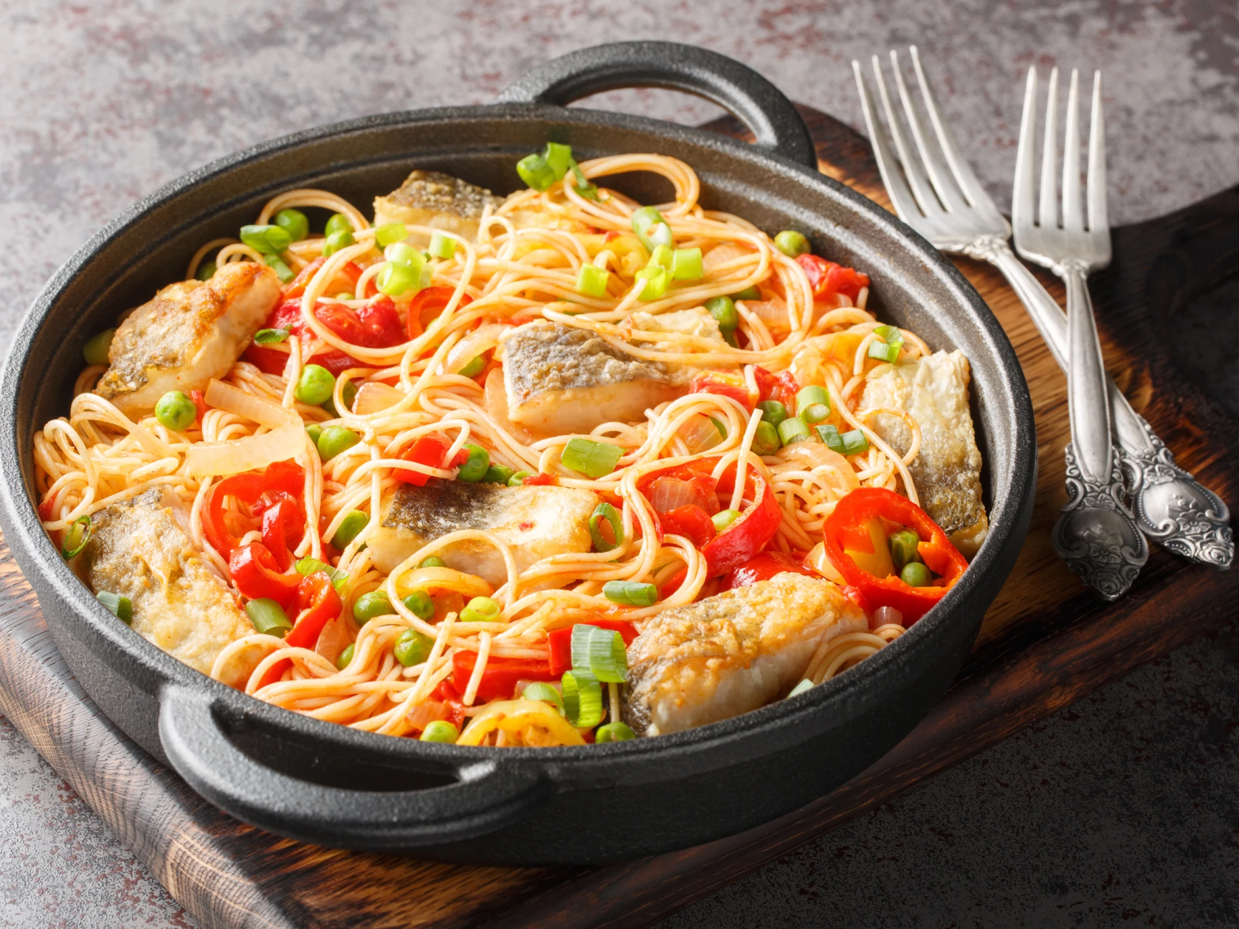 Spaghetti with white fish fillet, peppers, onions, green peas and tomato sauce